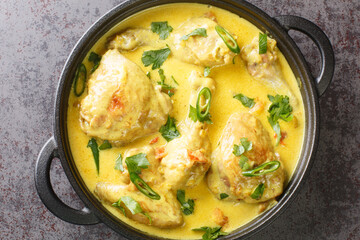 chicken in coconut curry sauce closeup in the pan on the table. Horizontal top view from above