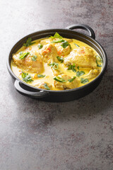 Kuku wa kupaka chicken in coconut milk with spicy, tomato, garlic and ginger closeup in the pan on the table. Vertical
