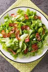 Southern Wilted Lettuce Salad With Hot Bacon Dressing closeup in the plate on the table. Vertical top view from above