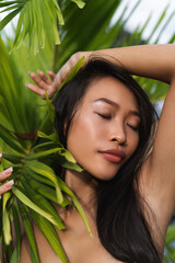 Beautiful asian thai woman with soft smooth clean dark tanned skin beauty portrait skincare positive posing with green leaves plump lips outdoor natural beauty