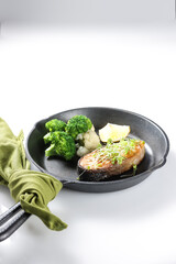 Fried salmon steaks with lemon butter sauce garnish with micro greens.