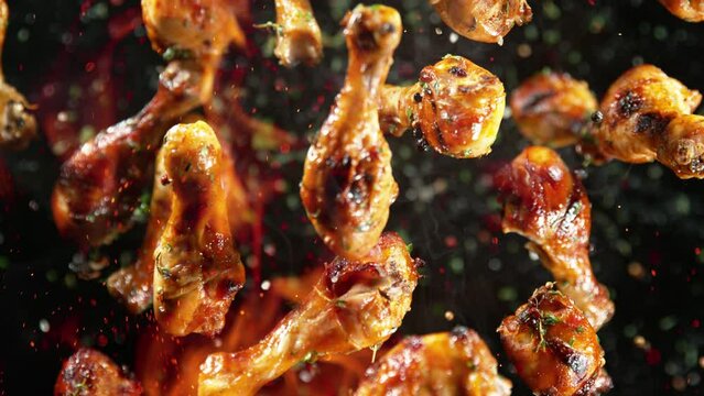 Super Slow Motion Shot of Grilled Spicy Chicken Drumsticks Flying Towards Camera at 1000fps.