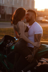 Couple hugging near motorbike at sunset