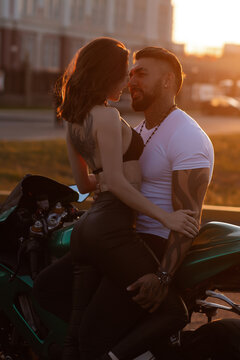 Couple hugging near motorbike at sunset