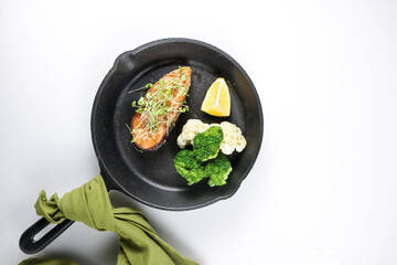 Fried salmon steaks with lemon butter sauce garnish with micro greens.