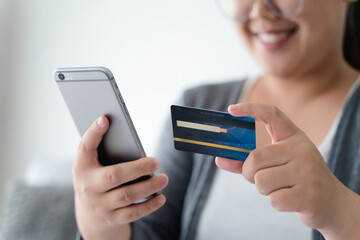 Woman holding credit card and using smartphone for online shopping, internet banking, e-commerce, spending money.