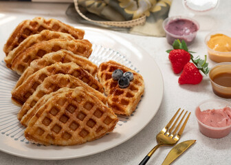 Croissant Waffle or its fa,mous names Croffle on white plate with white background. Served with various dipping sauce. Selective Focus