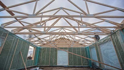 Low angle shot of builders nailing wooden planks on the roof with pneumatic nail guns in timelapse.