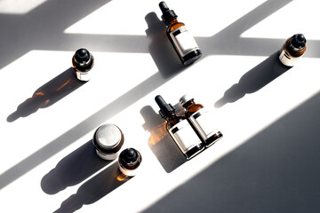Different dropper bottles with pipette and mocke up label on white background with hard light and shadow. Modern skin care routine and treatments with serum and oil