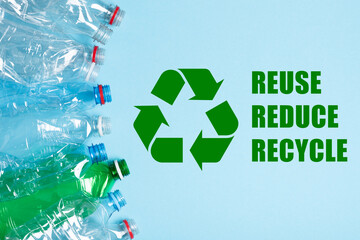 Single use plastic bottles and recycling symbol with reuse reduce recycle text on blue background