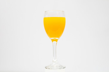 Orange juice in wine glass on white background