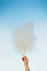 Holding Sweet Cotton Candy on Stick on Blue Sky background
