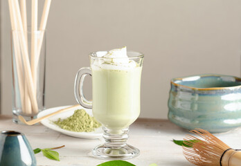 Matcha latte drink, green tea with milk in glass with accessories on light background.