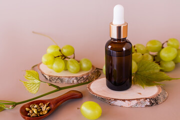 facial serum or cosmetic oil from grape seeds in a bottle with a pipette stands on a piece of wood and berries of ripe grapes. the concept of beauty.