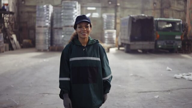 a portrait of an african american woman in a special green uniform is walking in a waste processing plant. Factory background. Processing of raw materials, recycling. Pollution control