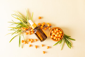 cosmetic bottle with pipette with an organic remedy based on sea buckthorn oil against of ripe berries. skin care and nutrition. top view.