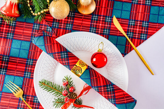 serving the Christmas table in the traditional colors of white, red, green. white plate, gold cutlery. top view.