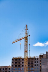 Fototapeta na wymiar Creation site with construction crane work on against blue sky background. View of industrial cranes. Concept of construction of apartment buildings and renovation of housing. Copy text space