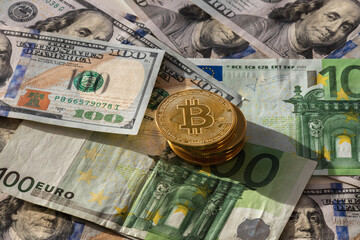 Pile of bitcoin coins over 100 dollar and 100 euros banknotes background. New decentralized monetary standard. Horizontal view with sunlight.