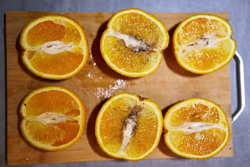 Naklejka na ściany i meble Rotten inside orange. Mold on fruit pulp. Spoiled orange on chopping board. Rottening fruit gradient. Cut in halves rotten orange fruit with fungus. Poisonous dangerous for health spoiled fruit macro.