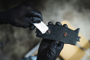 Auto mechanic applying brake grease lube on the back of a brake pads.