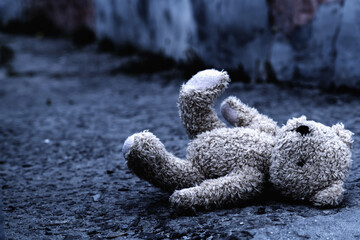 Teddy bear toy forgotten on the street as symbol of children's loneliness, pain, broken childhood...