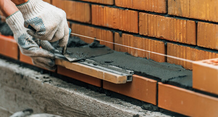 Mason trowels smears cement mortar on brick. Bricklaying when building house or stone fence.