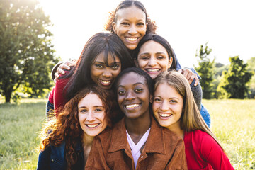 Fototapeta premium Group of cheerful young women looking at the camera, six different woman from all over the world, concept of integration, inclusion and friendship