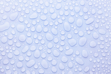 Water drops on soft light blue or violet, very peri background as elegant fresh trendy color pattern with shiny round drops, top view.