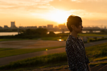 夕日 河川敷 ショートヘアの女性