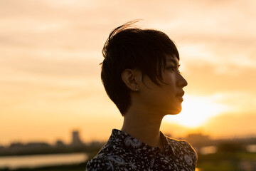 夕日 河川敷 ショートヘアの女性