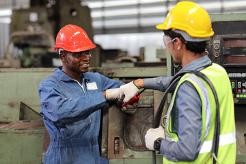 Happy smiling teamwork technician engineer or worker in protective uniform and hardhat make fist bumping celebrate successful together completed deal commitment at heavy industry manufacturing factory