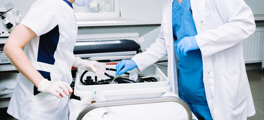 Doctor's hands in sterile gloves with tweezers. A doctor with tweezers after a colonoscopy takes a...