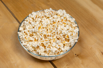 Popcorns in a glass bowl on wooden table