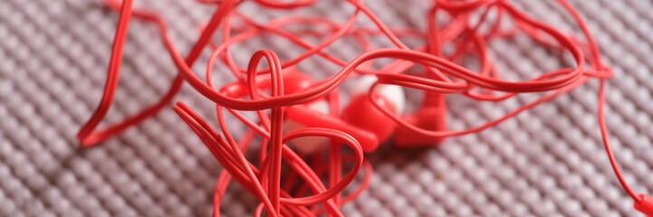 Tangled red wired headphones on gray background