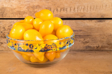 Small yellow tomatoes in a glass bowl. Closeup image of yellow pear tomatoes. Organic healthy food.