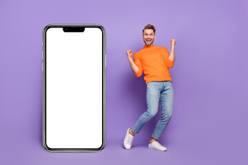 Full body photo of laughing screaming man excited to win new phone model isolated on purple color background