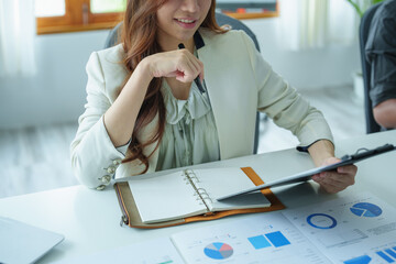 A portrait of a businesswoman holding a budget document and using computers and calculators placed...