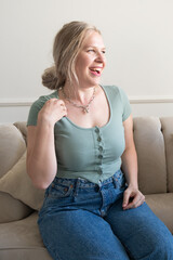 Plump blond woman laughing while sitting on the couch