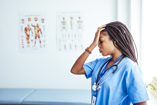 Exhausted Depressed Young Female Doctor Feels Mental Burnout At Work. Stressed Frustrated Physician Upset About Medical Failure, Healthcare Negligence, Having Headache Sits Alone At Desk In Hospital.