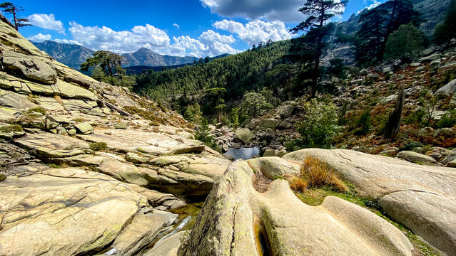 View of stream, trees, boulders and mountains from Cascades de Radule. On the way to the mountains Paglia Orba,  Corsica, France. 