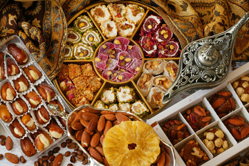 Eastern sweets with nuts, candy, metal vase, tea, dates on wooden background