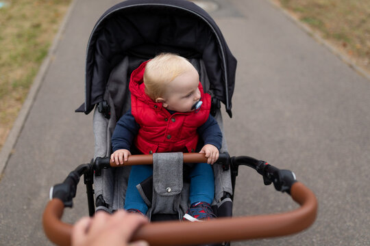 a small child with a pacifier in a baby carriage rides along the road