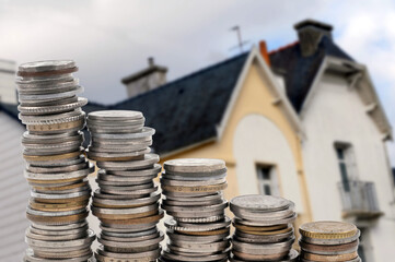 Concept d'investissement immobilier avec des piles de pièces de monnaie et une maison floue au...