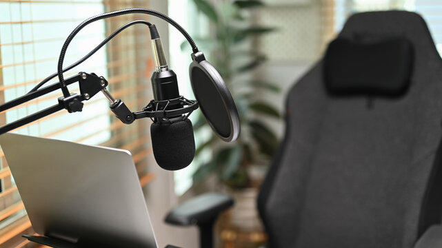 A professional condenser microphone, laptop computer in home studio interior. Entertainment, podcasts and technology concept