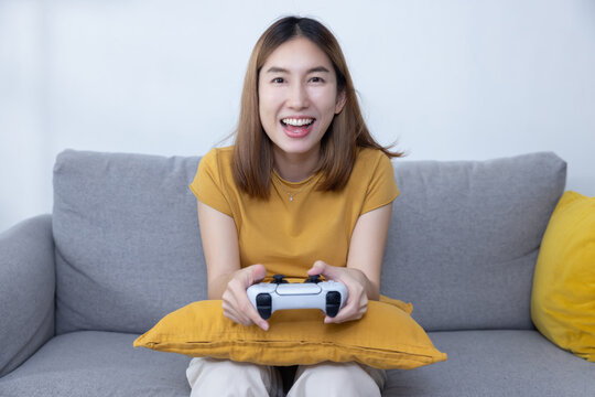 Asian Woman Play Console Game with a Game Controller on Sofa
