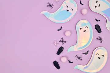 Cute pastel colored Halloween party flat lay with ghost shaped plates, spiders, pumpkins and...