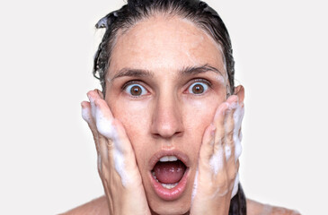 amazed shocked wow  face expression woman with wet hair or shampoo foam isolated on light beige...