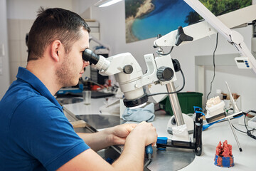 Technician in dental lab working under a microscope.