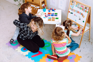 Teacher with children having fun and playing games, learning letters and numbers in kid development...
